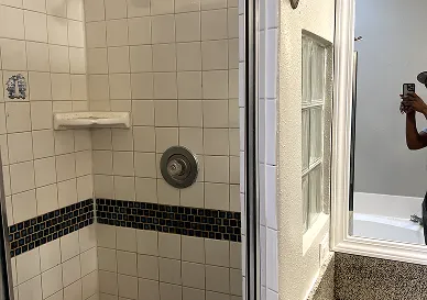 Before tile refinishing showing cracks and faded tiles in bathroom wall