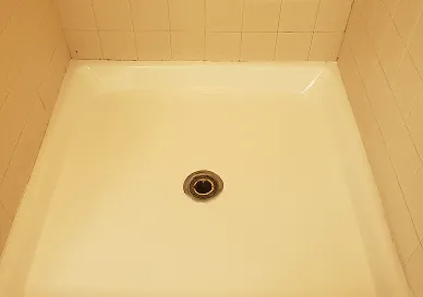 Before shower refinishing showing worn and dull tiles