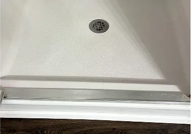 Before shower reglazing featuring worn-out grout and faded tiles